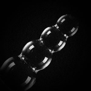 Anal Beads in a dark reflective image against a dark background