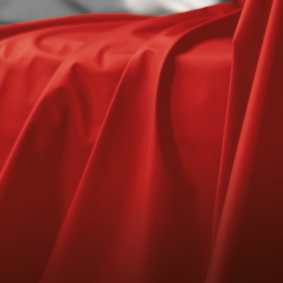 Close up of red Sheets of San Francisco Waterproof, wax proof & lube proof throw showing the fabric draped and pleated