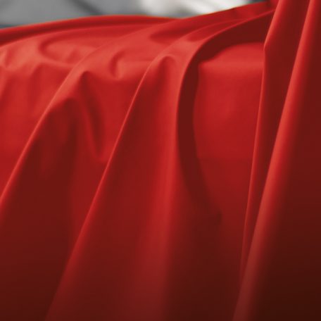 Close up of red Sheets of San Francisco Waterproof, wax proof & lube proof throw showing the fabric draped and pleated