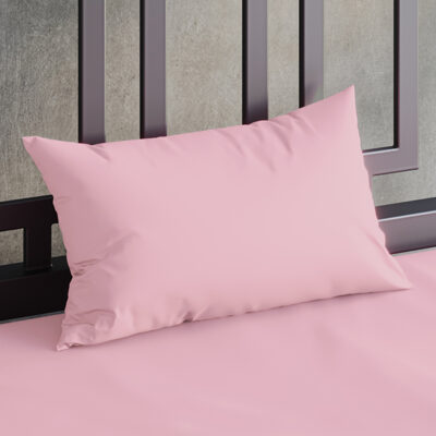 Close up of a Sheets of San Francisco Pink waterproof pillow case on a bed covered in a White Sheets of San Francisco fluidproof fitted sheet and against a black metal bedhead with the polished concrete wall behind showing through.